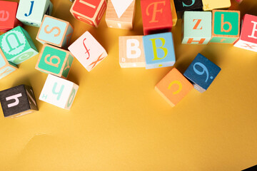 Colorful alphabet blocks scattered on a yellow surface Learning is fun
