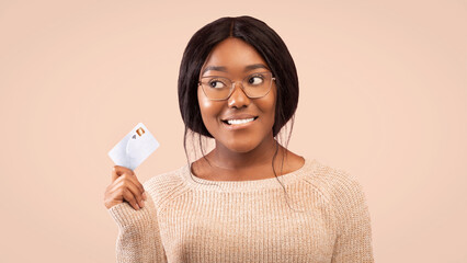 Smiling Black Woman Holding Credit Card Looking Aside Thinking About Something Standing Over Pink Background In Studio. Panorama