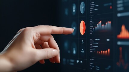 A hand interacts with a touchscreen displaying various data visuals, indicating user engagement with digital analytics or control systems.