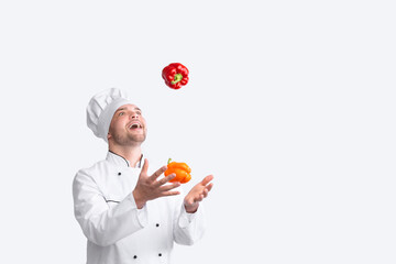 Vegetable Recipes. Excited Chef Man Juggling Throwing Sweet Peppers Standing In Studio Over White Background. Panorama