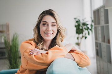 Photo portrait of nice cheerful girl sit couch enjoy weekend dressed orange garment spend pastime...