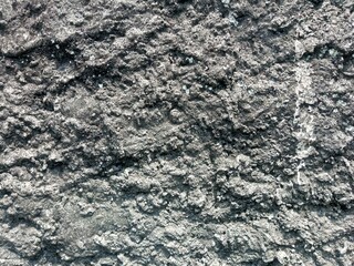 Obraz premium A detailed close-up of a rough, textured concrete wall surface. Ideal for backgrounds, design projects, or architectural concepts requiring an industrial or rugged aesthetic.