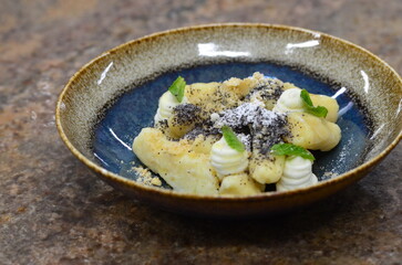 blue plate with traditional Czech sweet food, potato gnocchi with poppy seeds and cottage cheese, background of served food, fruit decorated