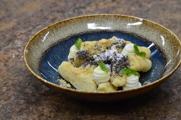 blue plate with traditional Czech sweet food, potato gnocchi with poppy seeds and cottage cheese, background of served food, fruit decorated