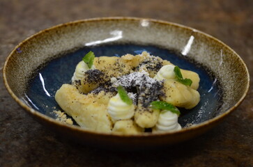 blue plate with traditional Czech sweet food, potato gnocchi with poppy seeds and cottage cheese, background of served food