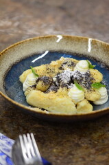 blue plate with traditional Czech sweet food, potato gnocchi with poppy seeds and cottage cheese, background of served food