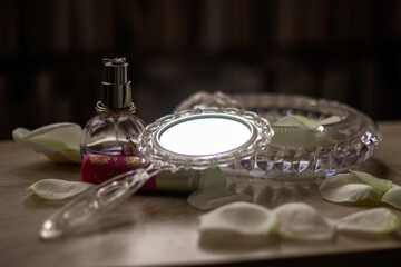 mirror, lipstick, perfume, rose petals on the table