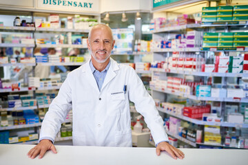 Pharmacist, man and portrait with smile at counter for customer service, medication and prescription. Dispensary, happy and mature medical worker at pharmacy for pharmaceutical, healthcare or supply