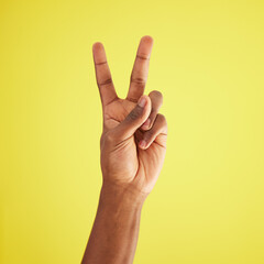 Naklejka premium Closeup, model and hand with peace, sign and support with agreement, respect and review on yellow studio background. African person, mockup and fingers for feedback, vote and emoji with icon and like