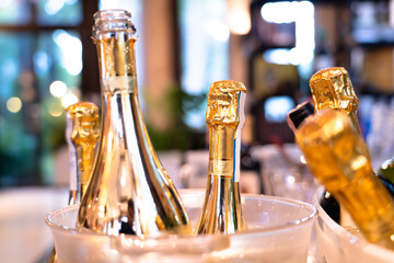 Close-up of several wine bottles in an ice bucket, bokeh light background