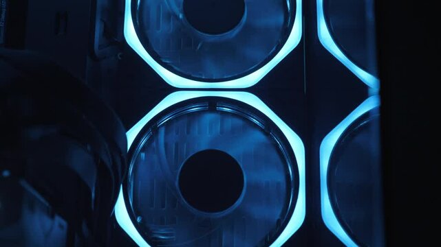 Gaming pc glowing in the dark - The system unit of a modern gaming computer. Working of computer cooling fan, the blue light. Fans Are Spinning Inside Computer. A modern computer gaming club.