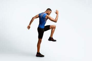High Knees. Energetic afro man doing fitness exercise, lifting leg and waving arm, free space