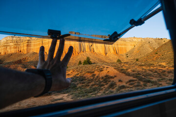 Here is a brief description of the image: A person's hand reaches out from the window of a camper...