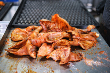 Seasoned pork ears prepared on a metal surface for smoking, showcasing the raw delicacy before it’s cooked on a grill.