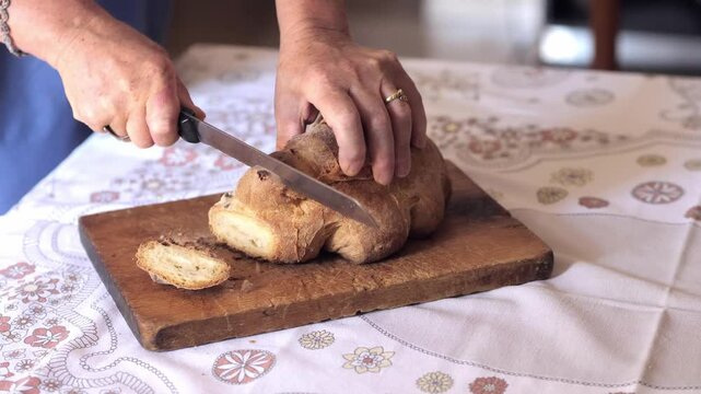 Hands slicing traditional Matera bread, Italy. The rustic and hearty bread is cut into slices, showcasing its texture and quality.