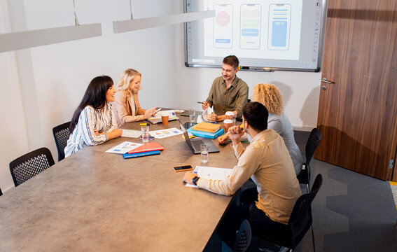 Group of business people sitting in a meeting room discussing a design for a smartphone application.