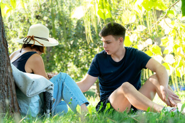 Mother and son spend time together sitting on the grass in the park.