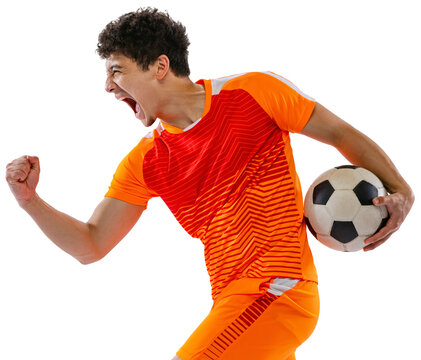 Fototapeta Winner emotions. Portrait of young man, football, soccer player posing with ball, wearing orange uniform isolated on white transparent background. Concept of sport, competition, active lifestyle, game