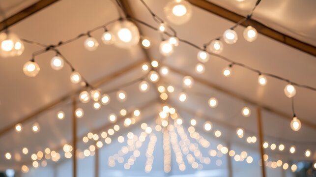 The inside of a white colored garden party tent with strings of white patio light bulbs. The sunshade is made of canvas fabric and has multiple poles holding up the center with hanging string lights.
