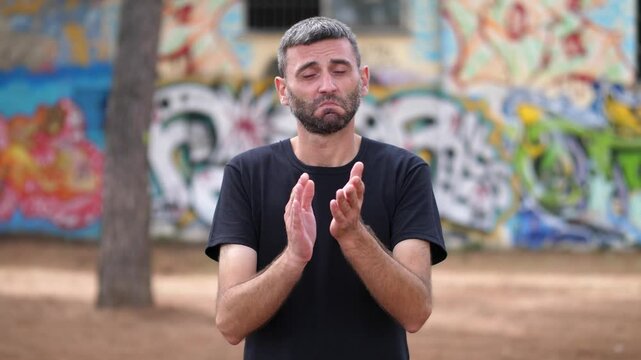 Medium shot of a man clapping in an ironic manner, indicating sarcasm or a humorous reaction. His clapping is exaggerated to convey a sense of mockery.