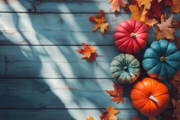 Autumn themed image showcasing four colorful pumpkins in red, orange, teal and green with scattered...