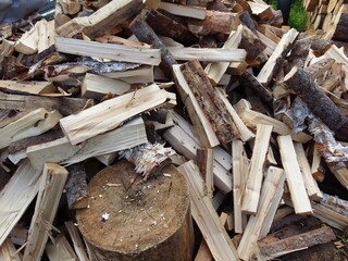 a pile of chopped firewood. The pieces of wood are of various sizes and shapes, with some having rough, bark-covered surfaces and others being more smooth and split. In the foreground