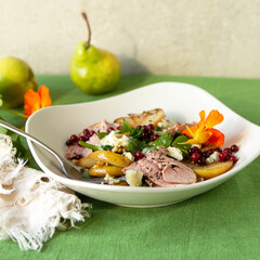 bowl of salad with duck breast, pear and blue cheese on table
