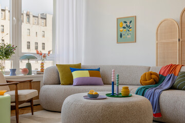 Stylish living room with a round ottoman, fresh floral arrangements, and colorful decor, creating a lively yet cozy atmosphere. Home decor and mock up poster frame.