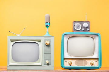 Retro TV, antique microphone and old radio front yellow background. Vintage style filtered photo