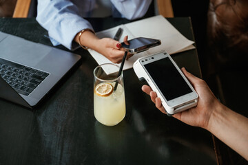 Money transfer. Woman is paying for the service in the restaurant