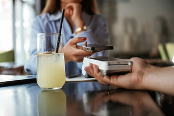 Contactless transfer. Woman is paying for the service in the restaurant