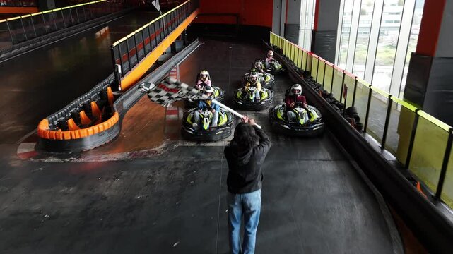 Group of go-kart racers crossing the finish line as an official waves the checkered flag.