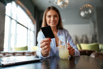 Giving the credit card. Young beautiful woman is in the restaurant
