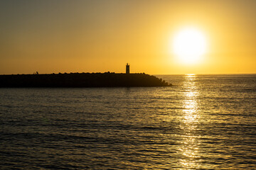 A breathtaking sunset at Nazaré, Portugal, with the sun dipping below the horizon, framed...