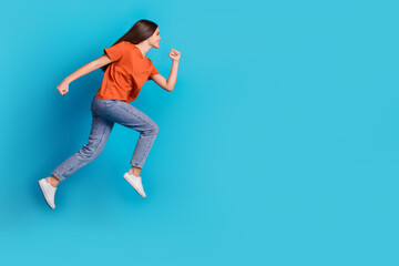 Full body photo of attractive teen woman running hurry empty space dressed stylish orange clothes isolated on blue color background © deagreez