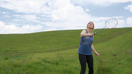 Young Woman Playing Badminton in Open Grassland