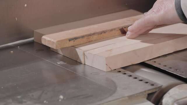 A man carpenter or joiner works with a grinding machine, holds in hand and uses a jointer to polishing wooden planks surface. A wood sanding process in a carpentry factory or workshop. Close up