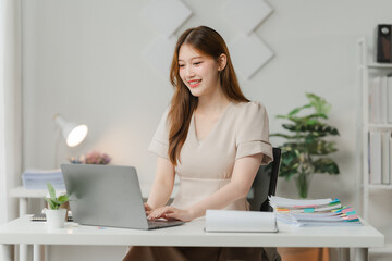 Focused and Confident: Young Asian Woman Working on Laptop at Home Office Desk.  