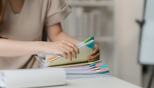 Organizing for Success: A young professional meticulously sorts through color-coded documents at her desk, embodying focus and productivity in a modern workspace. 