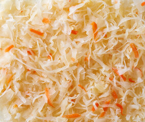 Close-up fermented white cabbage with carrot. Food background texture, top view.