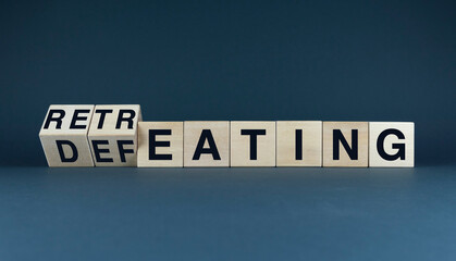 Obraz premium A conceptual image of wooden blocks spelling out the words Retreating and Defeating