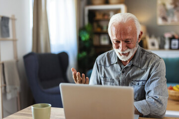 Senior man and video call on laptop in home for voip communication, social networking and chat. Elderly guy speaking on computer for virtual conversation, online contact and digital connection
