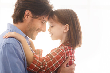 Fototapeta premium Close up of young father hugging his cute little daughter over white background, love and affectionate concept