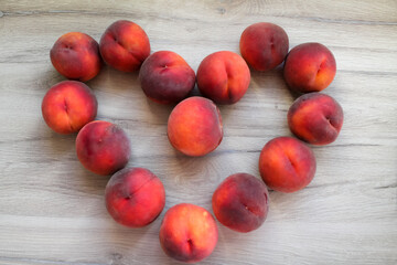 Peaches are laid out on the table in the shape of a heart. Flat lay