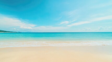 Relaxing tropical sandy beach with a soft-focus sea and clear blue sky, ideal for summer visuals.
