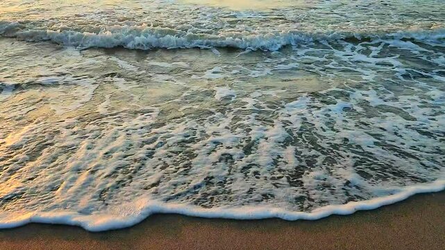 Sea waves rolling on a sandy beach on the seashore in summer during sunset sunrise. Nature. Natural background