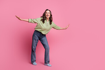 Full length photo of elegant grandmother woman in khaki shirt and jeans flying wings carefree isolated on pink color background