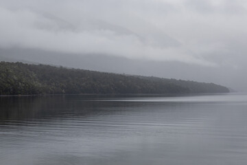 Layers of mountains through fog across the lake.