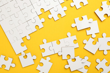 Naklejka premium White puzzle pieces on yellow background, top view