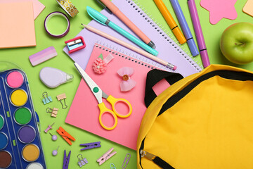 Backpack, different school stationery and apple on light green background, flat lay